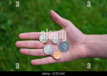 Monete britanniche tenute in palmo di mano Foto Stock