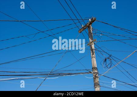 Palo elettrico con cavi aggrovigliati in modo anarchico. Concetto di reti energetiche complicate o sovraccaricate e pericolose Foto Stock