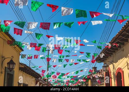 Ghirlande attraversate una strada tra gli edifici; San Cristobal de las Casas, Chiapas, Messico Foto Stock