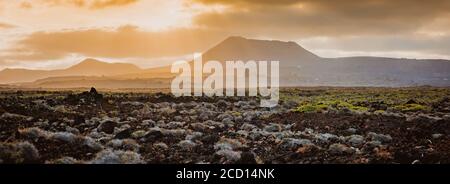 Bellissimo paesaggio di montagna con i vulcani al tramonto nel Parco Nazionale di Timanfaya a Lanzarote, Isole Canarie Foto Stock