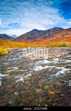 Kuyuktuvuk Creek e Brooks Mountains in colori autunnali sotto il cielo blu. Cancelli del parco nazionale artico e riserva, Alaska artica in autunno Foto Stock