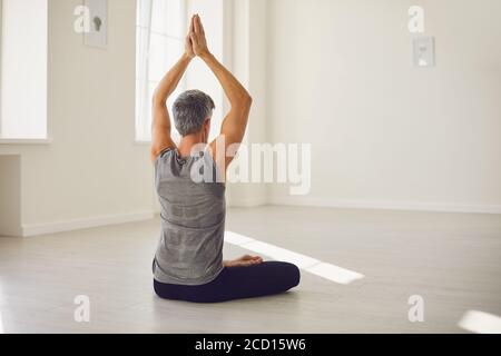 Yoga uomo. Il tipo barbuto sta esercitando lo yoga in una posizione del loto che siede in uno studio Foto Stock