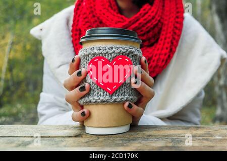 Primo piano tazza accogliente con forma a cuore in mano sulla natura. Picnic all'aperto di buon umore. Foto Stock