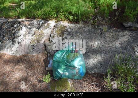 Sacchetto di plastica di rifiuti lasciato in un punto panoramico di bellezza nelle Highlands scozzesi, nella foresta di Loch Maree Foto Stock