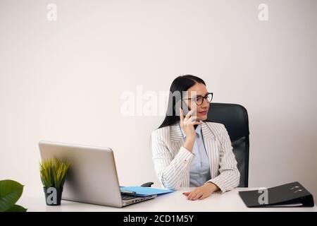 Allegra bruna signora con importante documento amichevole sorridente e sguardo con la fotocamera mentre navighi sul computer portatile alla scrivania dell'ufficio domestico Foto Stock