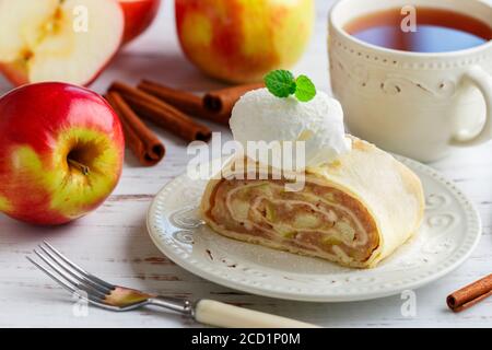 Strudel con mela e cannella. Tradizionale torta fatta in casa a strati con ripieno di frutta, servita con zucchero in polvere e gelato alla vaniglia. Delizioso pasticcio Foto Stock