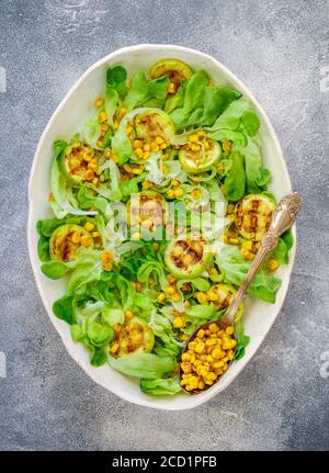 Deliziosa insalata di lattuga fresca con zucchine alla griglia, mais e formaggio di capra morbido con spezie e olio d'oliva. Messa a fuoco selettiva, vista dall'alto Foto Stock