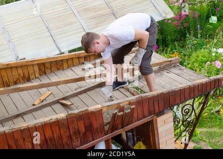 L'uomo batte una vecchia tavola di legno marcio con un martello Foto Stock
