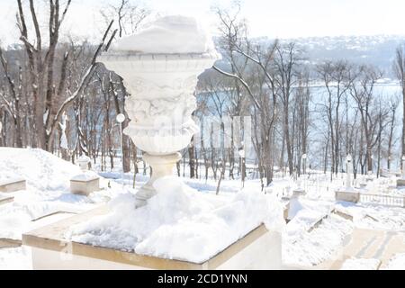 Vaso di fiori coperto di neve nel parco invernale Foto Stock