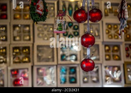 Baubles di Natale appesi di fronte a una varietà di blurry Scatole con baubles di Natale su un mercato tedesco di Natale Foto Stock