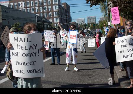 Portland, Oregon, Stati Uniti. 25 Agosto 2020. Vestita con una tuta da salto dipinta con buste colorate, LAURA GLAZER, centro di Portland, Oregon, ha un cartello con la scritta ''The mail Matters'' mentre partecipa a un Day of Action al di fuori dell'East Portland Post Office martedì 25 agosto 2020. GLAZER ha detto, ''il servizio postale è un modo per connettersi a toehr peoole. È un thread che collega tutti noi per quanto ci riguarda ciò che crediamo. Lettere e pacchetti sono anche un modo per inviare un pezzo di noi stessi a persone che amiamo o che vogliamo amare.'' Migliaia di persone in tutto il paese partecipate Foto Stock