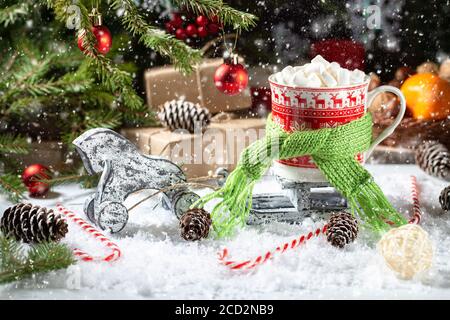 Natale prima colazione con neve, regali, abeti e tangerini. Tazze rosse con cioccolata calda e marshmallows con frutta e coni d'arancia. Buon Cristo Foto Stock