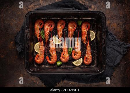 Vista dall'alto dei gamberi del re su un vassoio posteriore nero pronto per la cottura Foto Stock