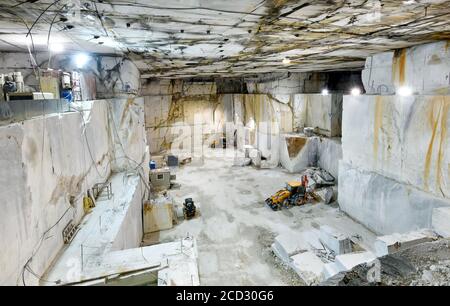 All'interno di un albero di montagna in una miniera di marmo di Carrara che mostra grandi blocchi di marmo bianco e attrezzature per impieghi pesanti In Toscana Foto Stock