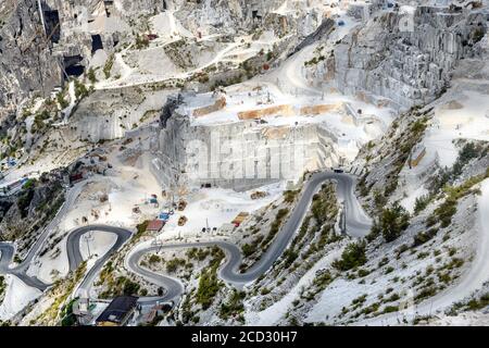 Vista panoramica delle cave di marmo di Carrara in una montagna ripida valle che mostra l'estrazione a getto aperto e una strada tortuosa in Toscana Italia Foto Stock