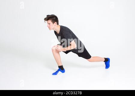 Un ragazzo in una t-shirt sportiva nera e shorts, sneakers blu, treni Foto Stock