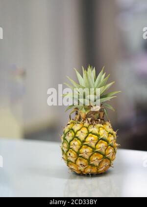 Ananas messo sul tavolo di vetro sfondo sfocato Foto Stock