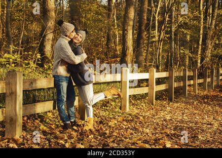 Coppia giovane indossando maglioni caldi e cappelli di lana nel parco di soleggiata giornata autunnale Foto Stock