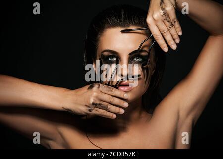 Bella donna con sbavature di trucco sul suo viso e spazzole mascara rotte Foto Stock