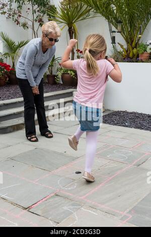 Una nonna insegna a sua nipote un gioco tradizionale di hopscotch. Foto Stock