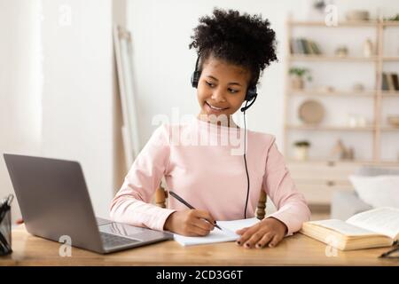 Black Girl che usa il computer portatile fare le esercitazioni in linea seduto indoor Foto Stock