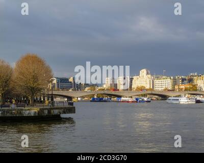 Vista lungo il Tamigi sul ponte di Waterloo fino alla Shell Mex House, 80 Strand, e alla stazione di Charing Cross in inverno sotto il cielo grigio Foto Stock