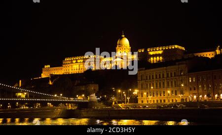 Europa dell'Est, Ungheria, Budapest, Palazzo reale (Kiralyi palota) di notte, il Danubio in primo piano Foto Stock