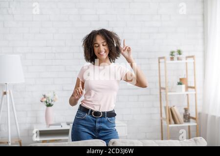 Musica preferita al lavoro a casa. Donna afro-americana felice in cuffie danzanti Foto Stock