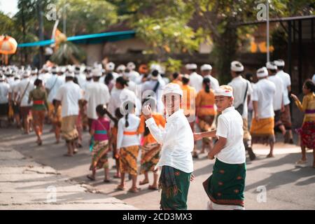 Galungan Holiday.Feste processione. Due ragazzi in primo piano. Isola di Bali, Indonesia.26.12.2018. Foto Stock