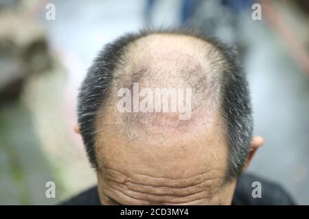 Il Sig. Jiang, un uomo degli anni settanta, pratica lo yoga in modo speciale, in piedi capovolti con la testa mentre tiene un ombrello con il piede su un ro Foto Stock