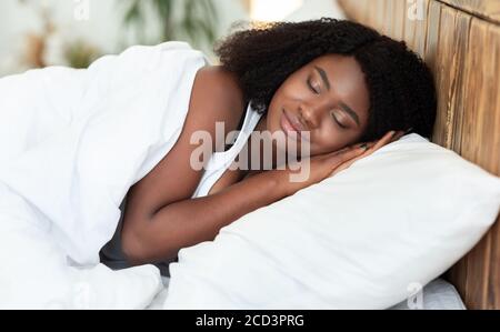 Giovane bella donna nera che dorme nel suo letto Foto Stock