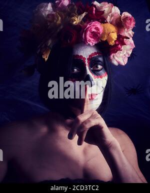donna di aspetto caucasico è vestita in una corona di rose multicolore. Cranio da zucchero Halloween Makeup, Calavera Catrina Foto Stock