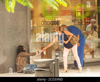 Las Palmas, Gran Canaria, Isole Canarie, Spagna. 26 agosto 2020. Un acquirente che indossa maschere a Las Palmas su Gran Canaria dà denaro a una persona senza casa come Covid casi aumentare nelle isole Canarie. Ci sono stati più casi in agosto che i mesi di febbraio a luglio combinati. Credit: Alan Dawson/Alamy Live News Foto Stock