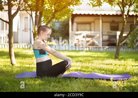 Donna incinta nel giardino pratica yoga. Mattina d'estate. Foto Stock