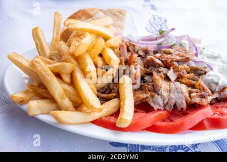 Souvlaki greco, cibo tradizionale greco, carne di maiale e patatine fritte con cipolla e salsa tzatziki. Foto Stock