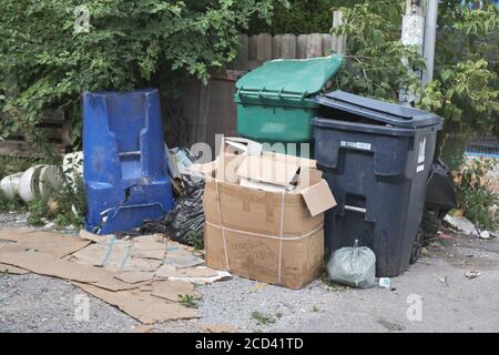 Disordinato spazzatura nel vicolo posteriore che circonda vari contenitori di riciclaggio. Toronto, Canada Foto Stock