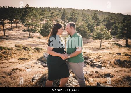 Felice e giovane coppia incinta abbracciando nella natura Foto Stock