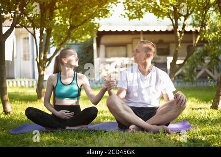 Coppia di amanti che praticano lo yoga in giardino. Donna incinta. Mattina d'estate Foto Stock