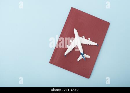 Aereo sulla copertura del passaporto rosso. Concetto di viaggio. Sfondo blu Foto Stock