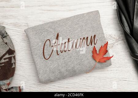 Pullover grigio con l'iscrizione Autunno e foglia rossa. Concetto alla moda Foto Stock
