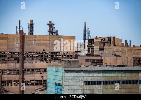 Vecchi edifici abbandonati della metallurgia sovietica con finestre rotte e camini arrugginiti sul cielo blu. Taraz città. Foto Stock