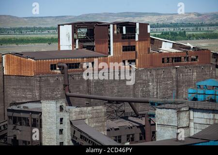 Vecchio sovietico non utilizzato obsoleto arrugginito fabbrica costruzione di metallurgia acciaio impianto sul cielo blu e le montagne sfondo. Taraz città. Foto Stock