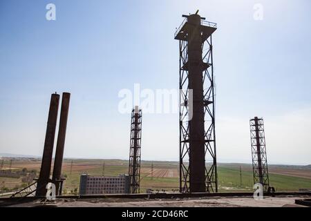 Vecchia fabbrica di metallurgia sovietica non utilizzata costruzione e camini fabbrica sul cielo blu e sfondo steppa. Città di Taraz, Kazakistan. Foto Stock