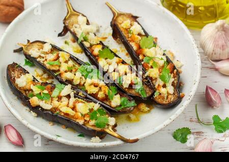 Melanzane al forno con olio d'oliva, aglio, prezzemolo o coriandolo (coriandolo) noci e pangrattato. Spuntino gourmet di verdure mediterranee in un plat bianco Foto Stock