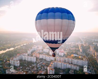 Mongolfiera colorata che sorvola la piccola città europea al tramonto estivo, regione di Kiev, Ucraina Foto Stock