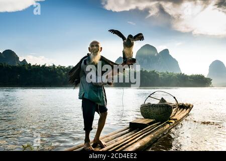 In questa foto non datata, un vecchio pescatore e il suo pesce cormorano su una zattera di bambù sul fiume li, conosciuto anche come li Jiang, Guilin città, il GU della Cina sud-occidentale Foto Stock