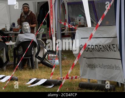 Berlino, Germania. 26 Agosto 2020. Con una maschera 'Anonymus' sul retro della sua testa, un partecipante di un campo dell'iniziativa di Stoccarda Querdenken 711 è seduto non lontano dalla Cancelleria. Gli attivisti hanno in programma di rimanere lì fino alla fine di settembre. Credit: Paul Zinken/dpa-Zentralbild/dpa/Alamy Live News Foto Stock