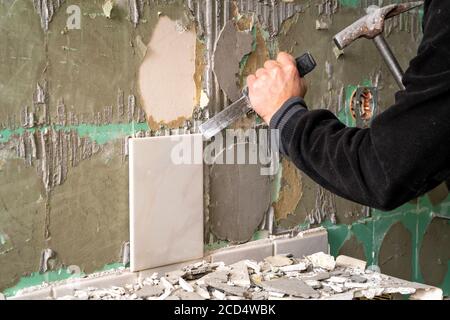 Preparazione di riparare il bagno. L'uomo la rimozione di vecchie piastrelle. Foto Stock