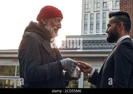 Vecchio mendicante chiedere dei soldi, uomo d'affari che cammina per strada ha risposto alla richiesta. Concetto di povertà e di questione sociale Foto Stock