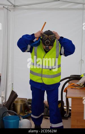 Il lavoratore mette sulla maschera a gas per proteggere contro il gas in emergenza Foto Stock